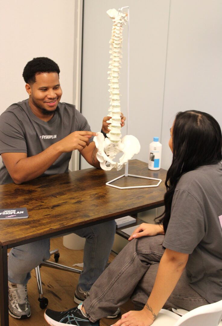 Fysiotherapeut legt met wervelkolommodel de oorzaak van acute lage rugpijn uit bij Fysioplan