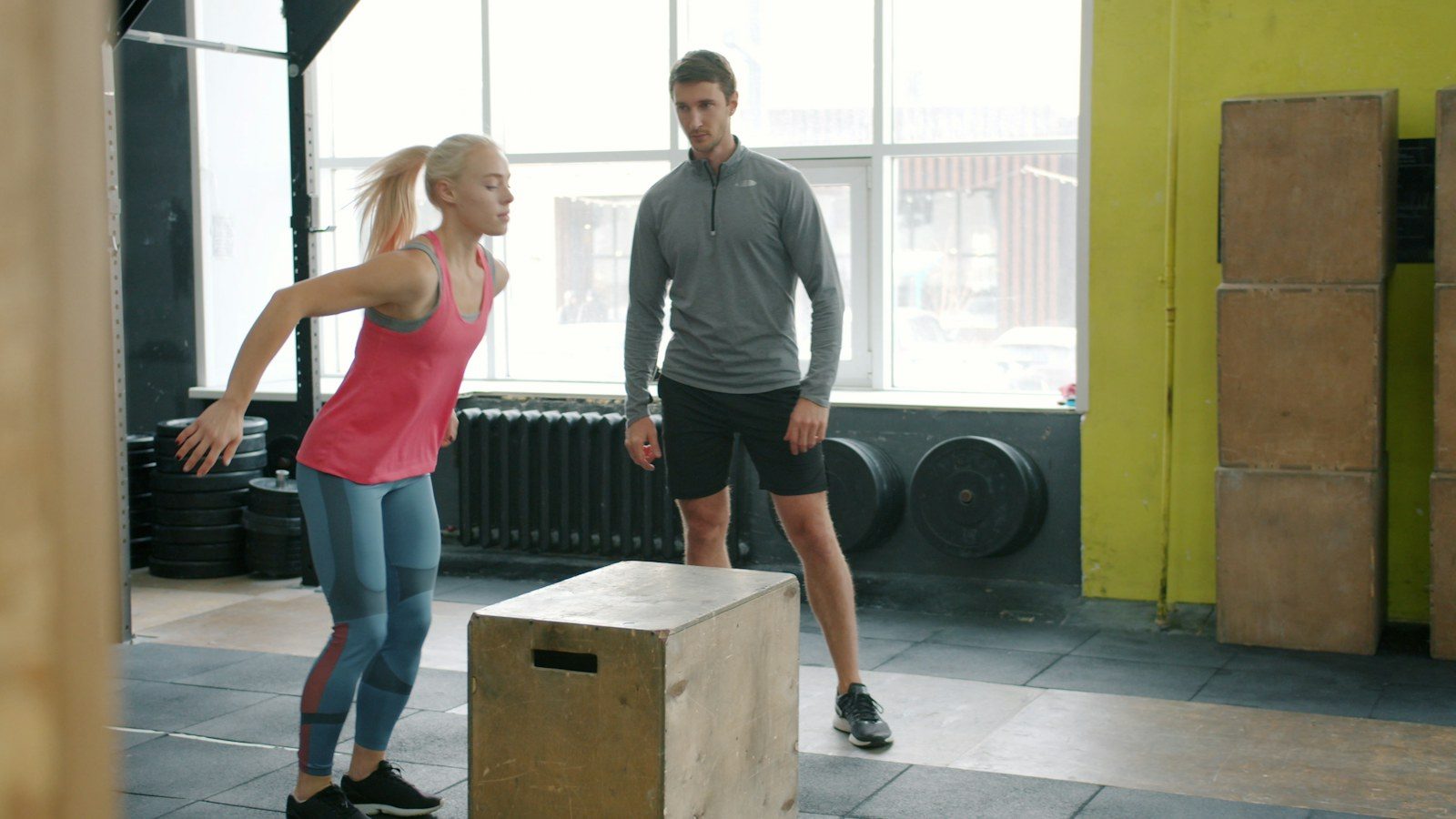 Sporter springt op een box terwijl een trainer meekijkt