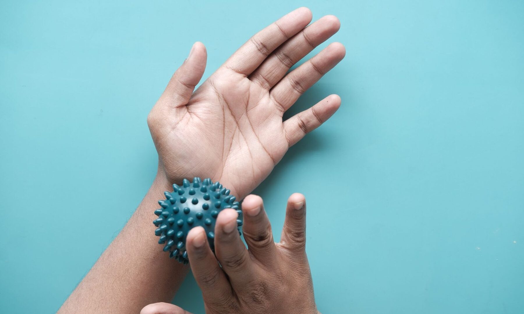 Hand die een massagebal rolt tegen tintelende vingers