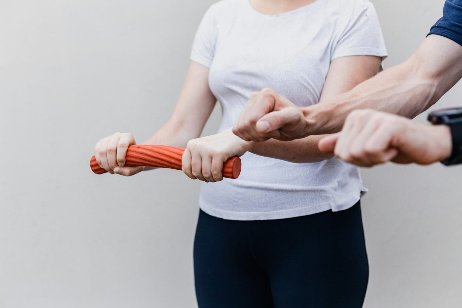 Oefening voor de onderarm met een flexibele staaf, begeleid door een fysiotherapeut