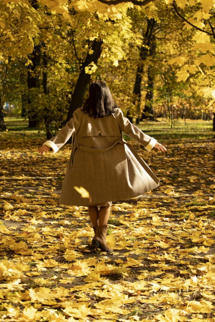 Vrouw wandelt door een park vol herfstbladeren