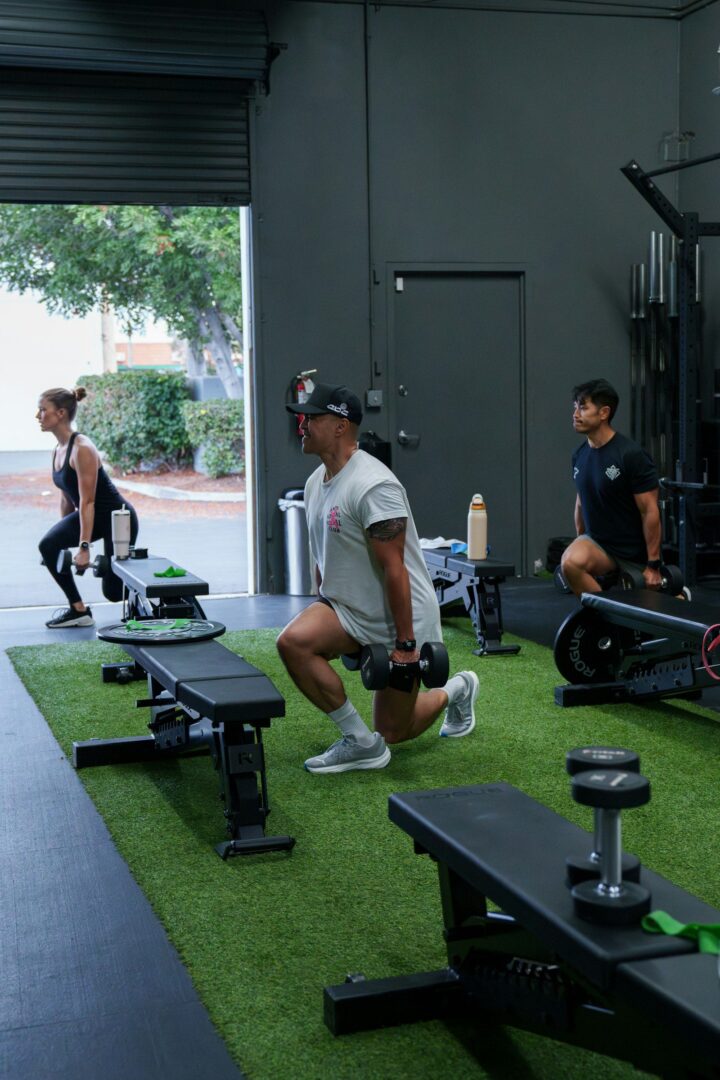 Groep doet samen lunges met dumbbells in de gym