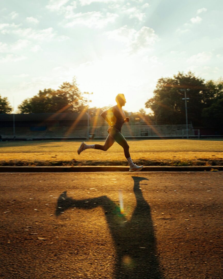 Hardloper sprint over de atletiekbaan bij zonsondergang