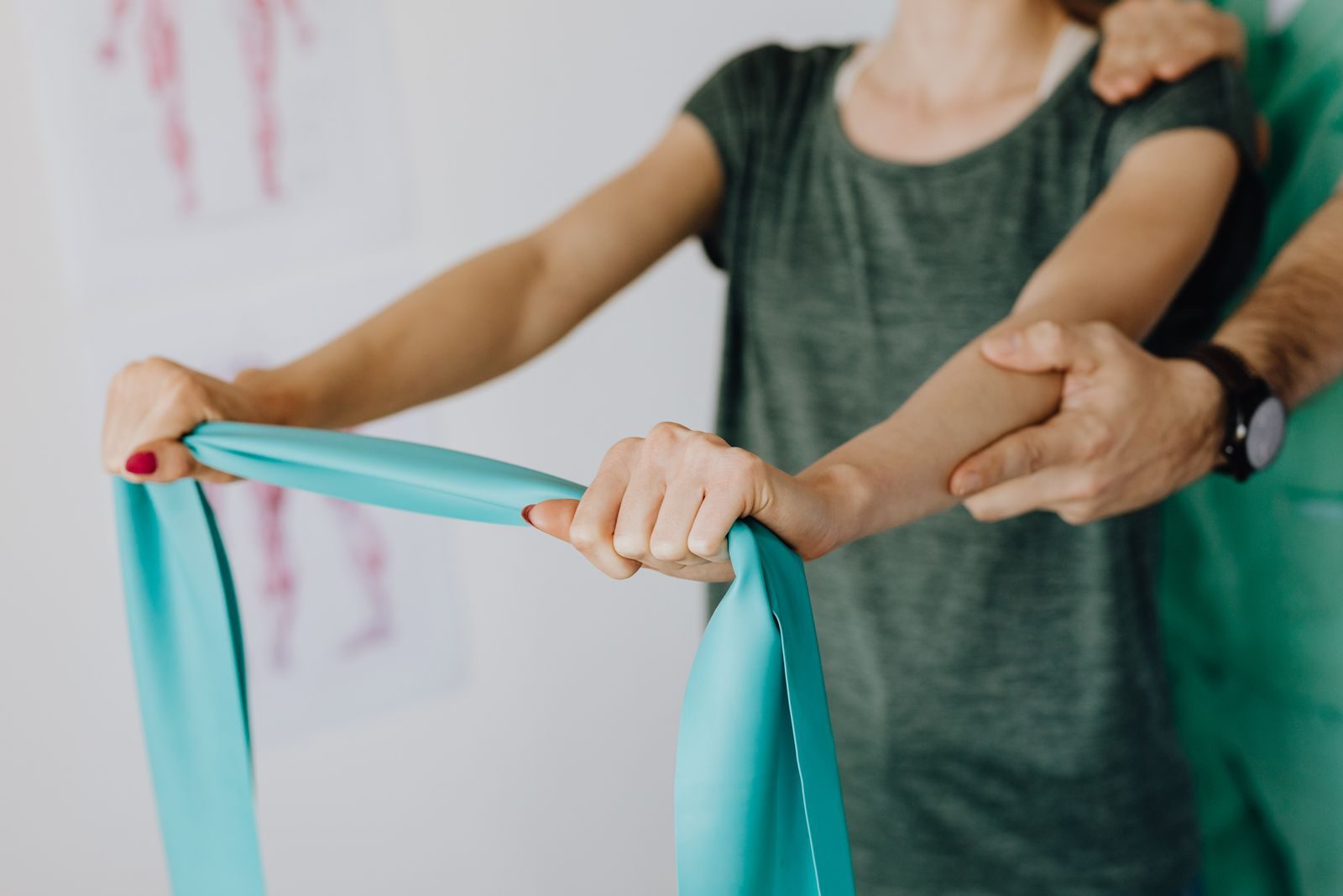 Fysiotherapeut begeleidt een schouderoefening met een elastische band